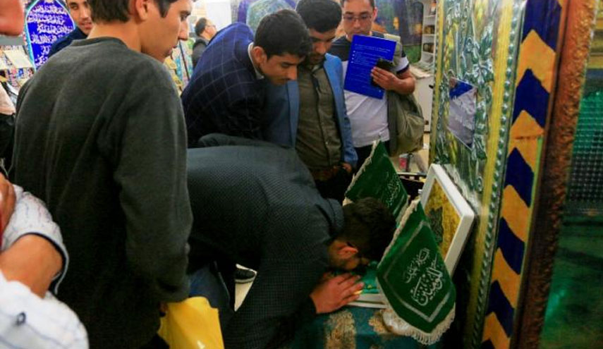 بالصور..رواد معرض طهران الدولي للكتاب يتبركون براية الامام علي (ع)